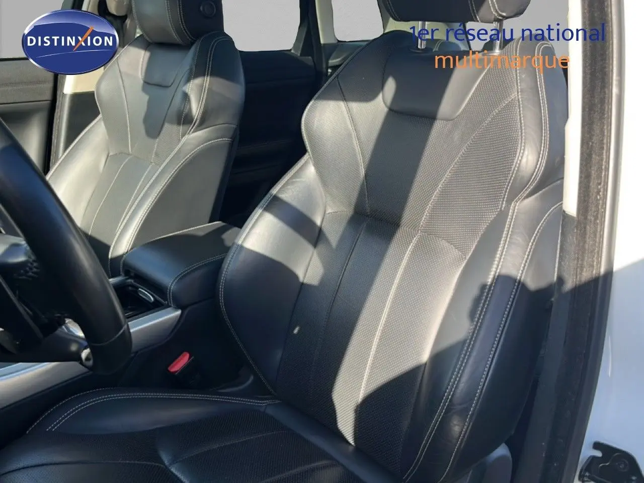 Gros plan sur les sièges avant en cuir noir du Range Rover Evoque blanc, avec détails de couture visibles.