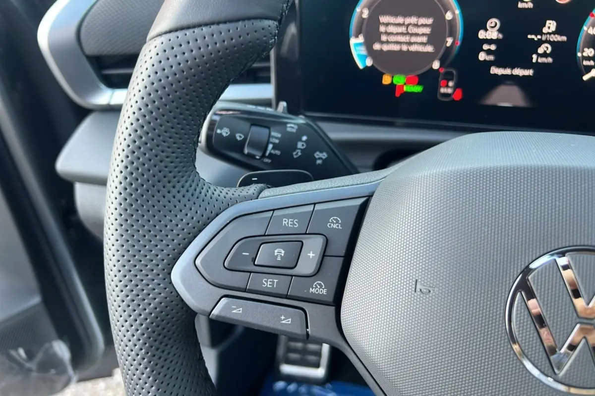 Gros plan sur le volant cuir perforé gris du Volkswagen T-Roc 2026 avec commandes multifonctions et tableau de bord digital.