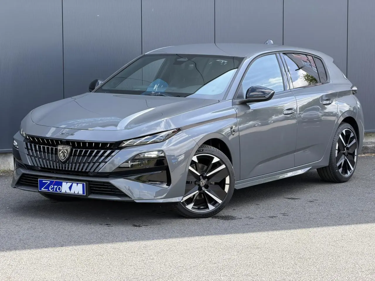 Peugeot 308 NV Hybrid gris Selenium vue 3/4 avant, jantes alliage bi-tons et calandre distinctive noire.