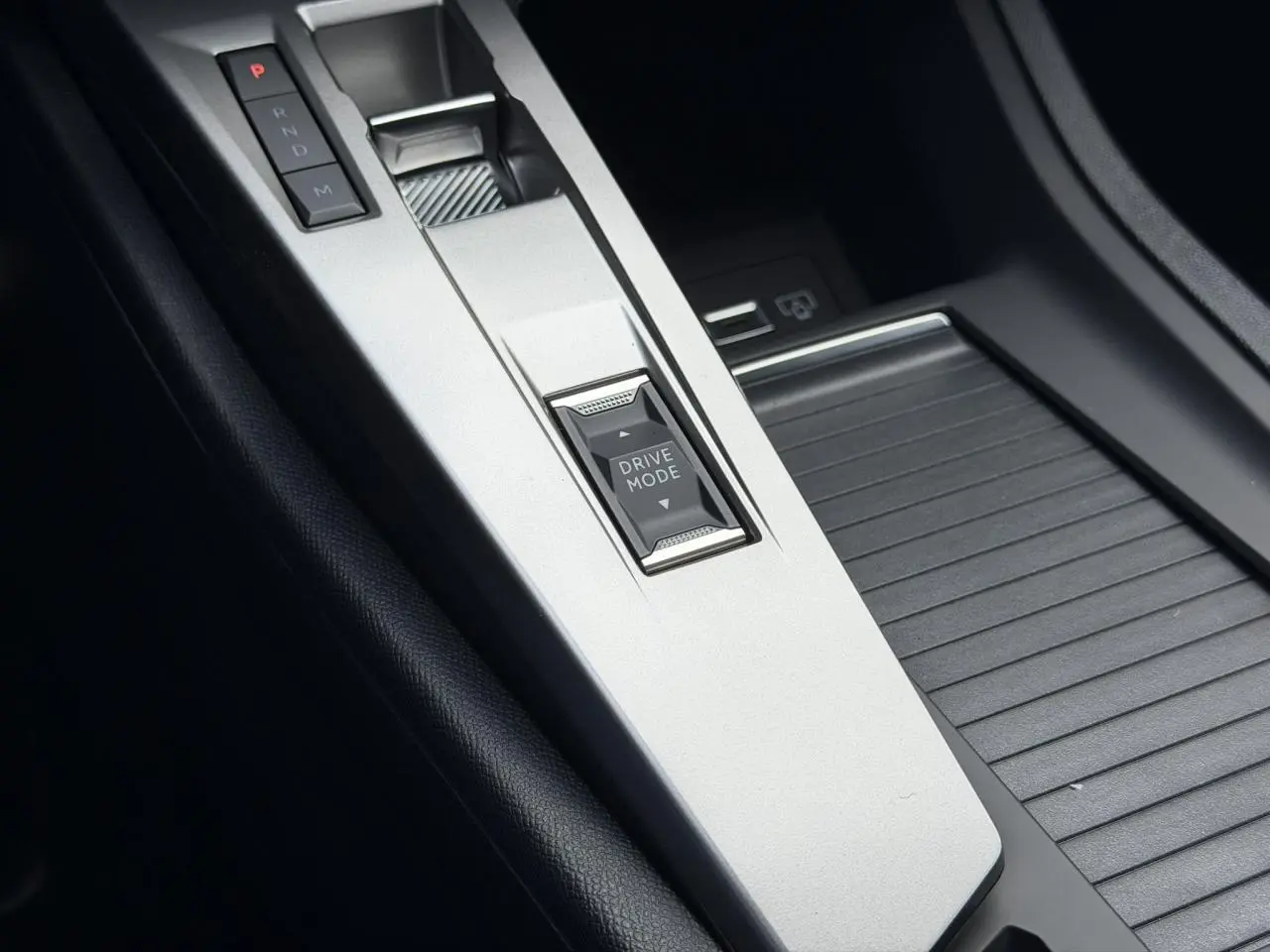 Gros plan sur la console centrale argentée du Peugeot 308 NV Hybrid avec bouton Drive Mode et levier de vitesses automatique.