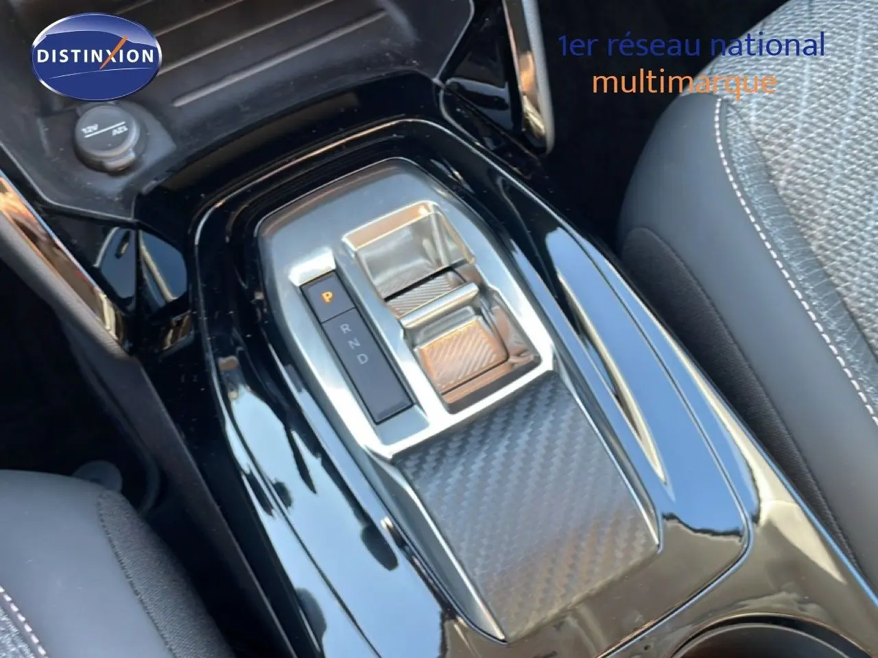 Gros plan sur la console centrale noire laquée de la Peugeot 208 Hybrid 110ch, mettant en valeur la commande de boîte automatique.