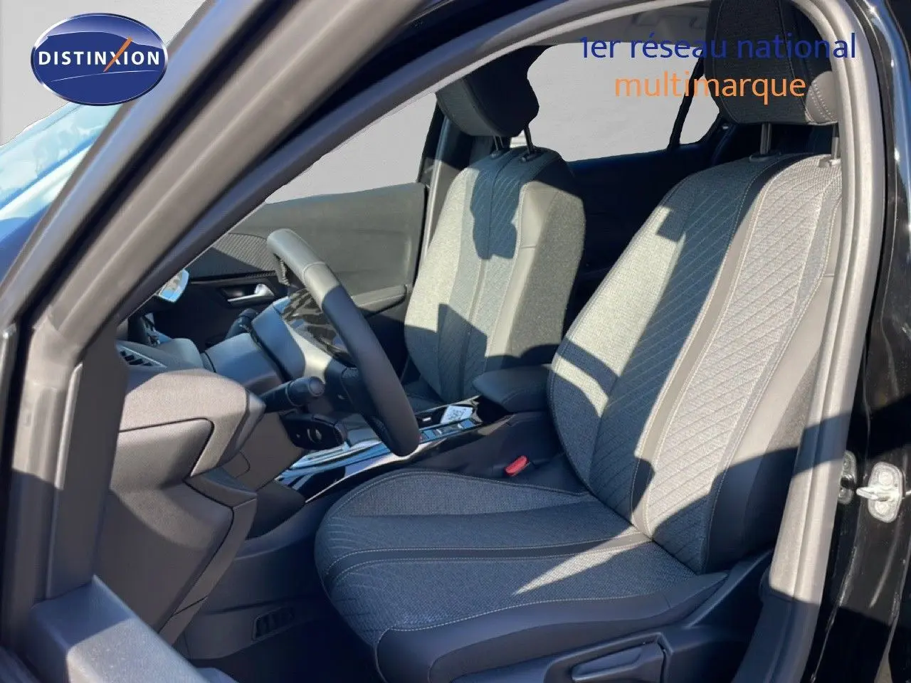 Vue intérieure côté conducteur de la Peugeot 208 Hybrid 110ch Allure 2026, sièges tissu gris et noir, volant multifonction.