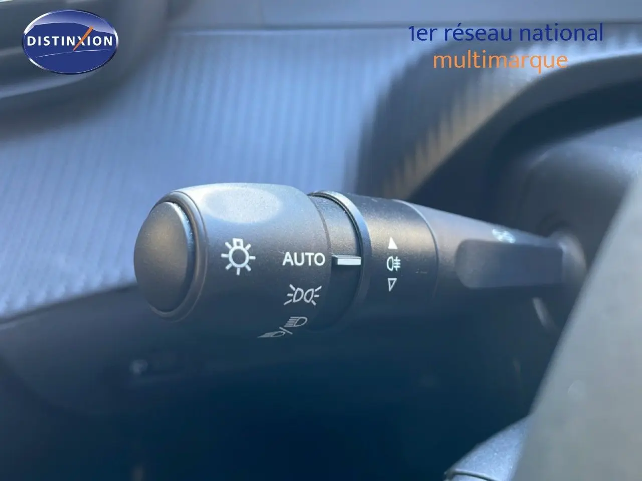 Gros plan sur la commande des feux avec fonctions automatiques, dans l’habitacle d’une Peugeot 208 noire.