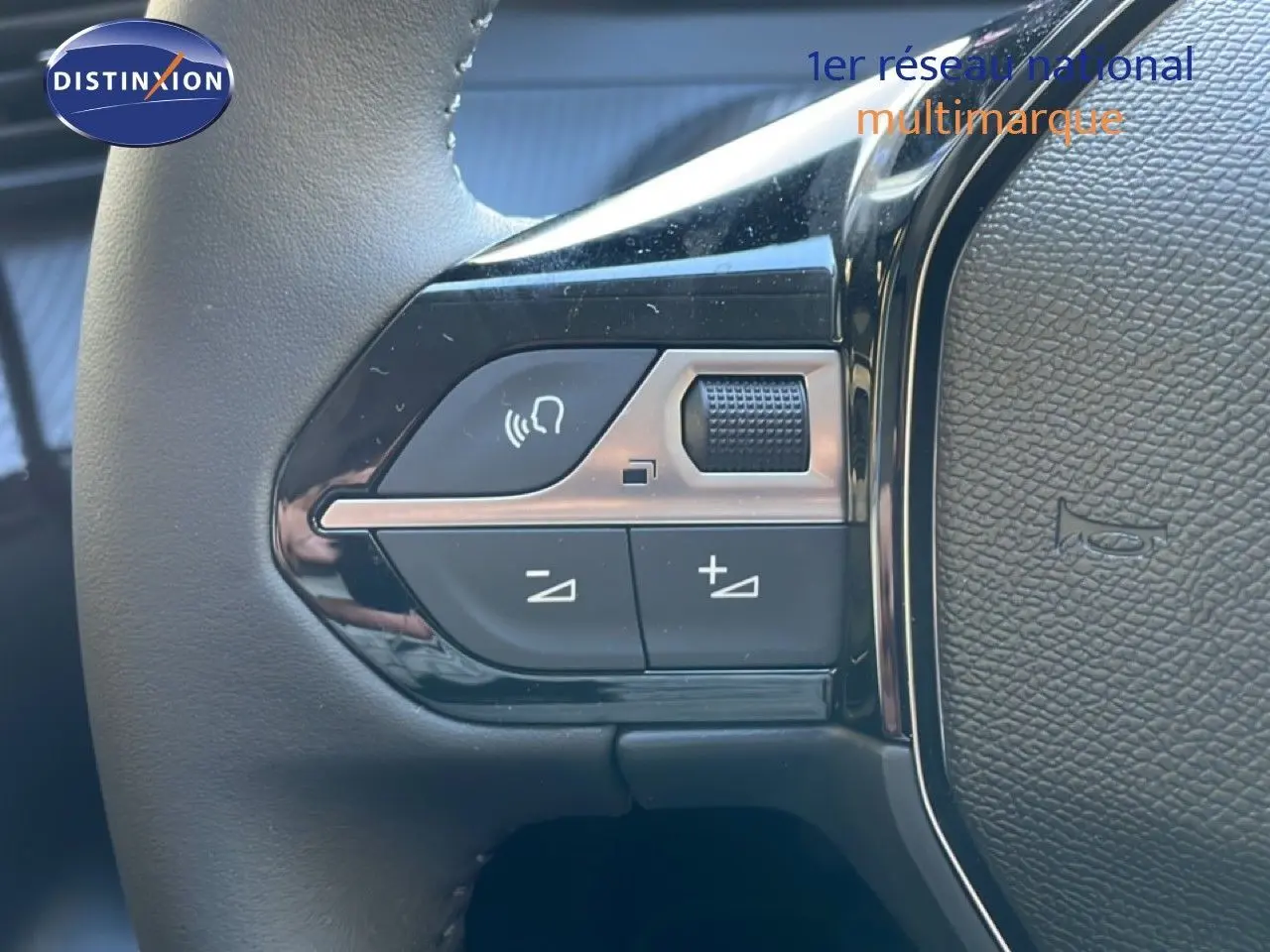 Gros plan sur les commandes de volume et téléphone au volant de la Peugeot 208 Hybrid 110ch finition Allure noire.