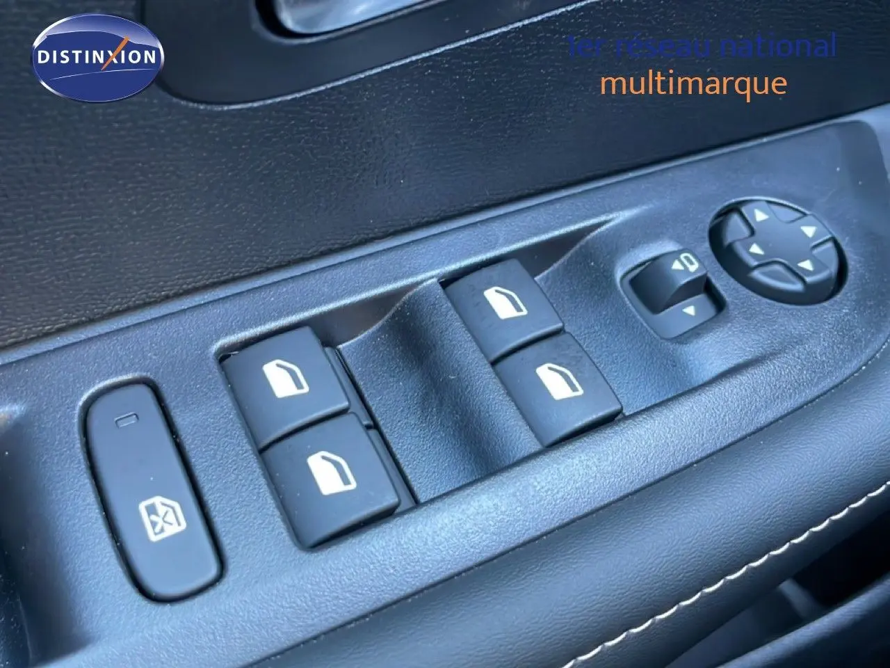 Gros plan sur les commandes de lève-vitres et réglage des rétroviseurs côté conducteur d’une Peugeot 208 noire.