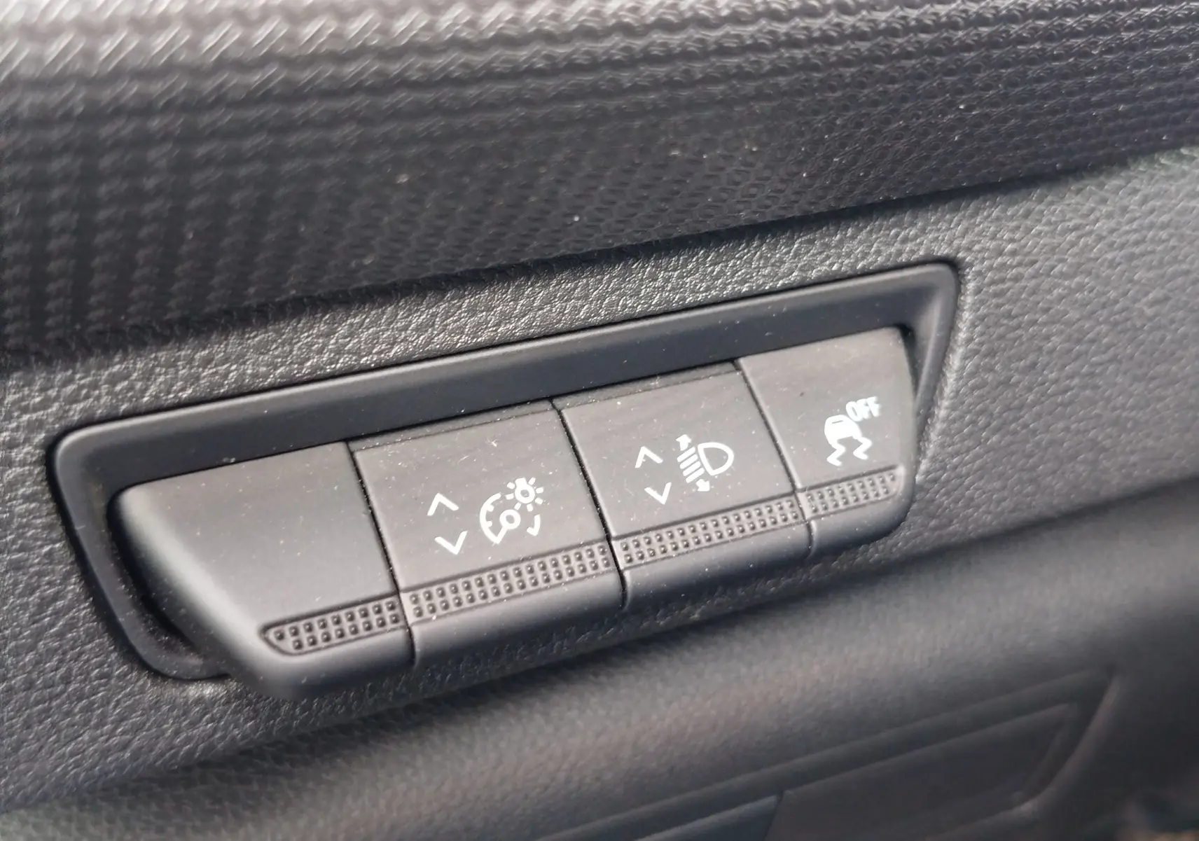 Gros plan sur les boutons de réglage d'éclairage et de contrôle de stabilité dans l'habitacle noir du Renault Kangoo blanc.