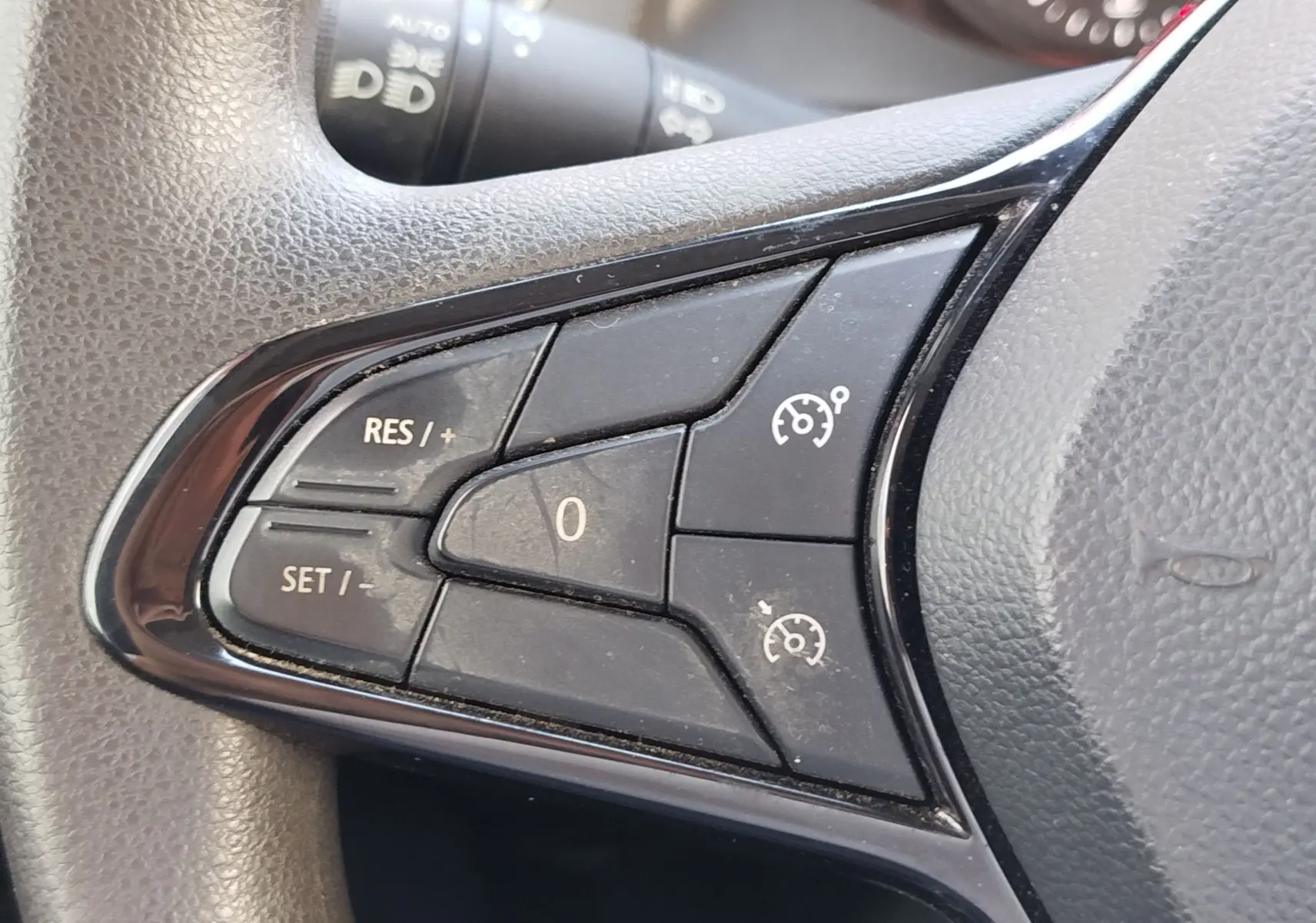 Gros plan sur les commandes de régulateur de vitesse au volant côté gauche du Renault Kangoo blanc 2023.