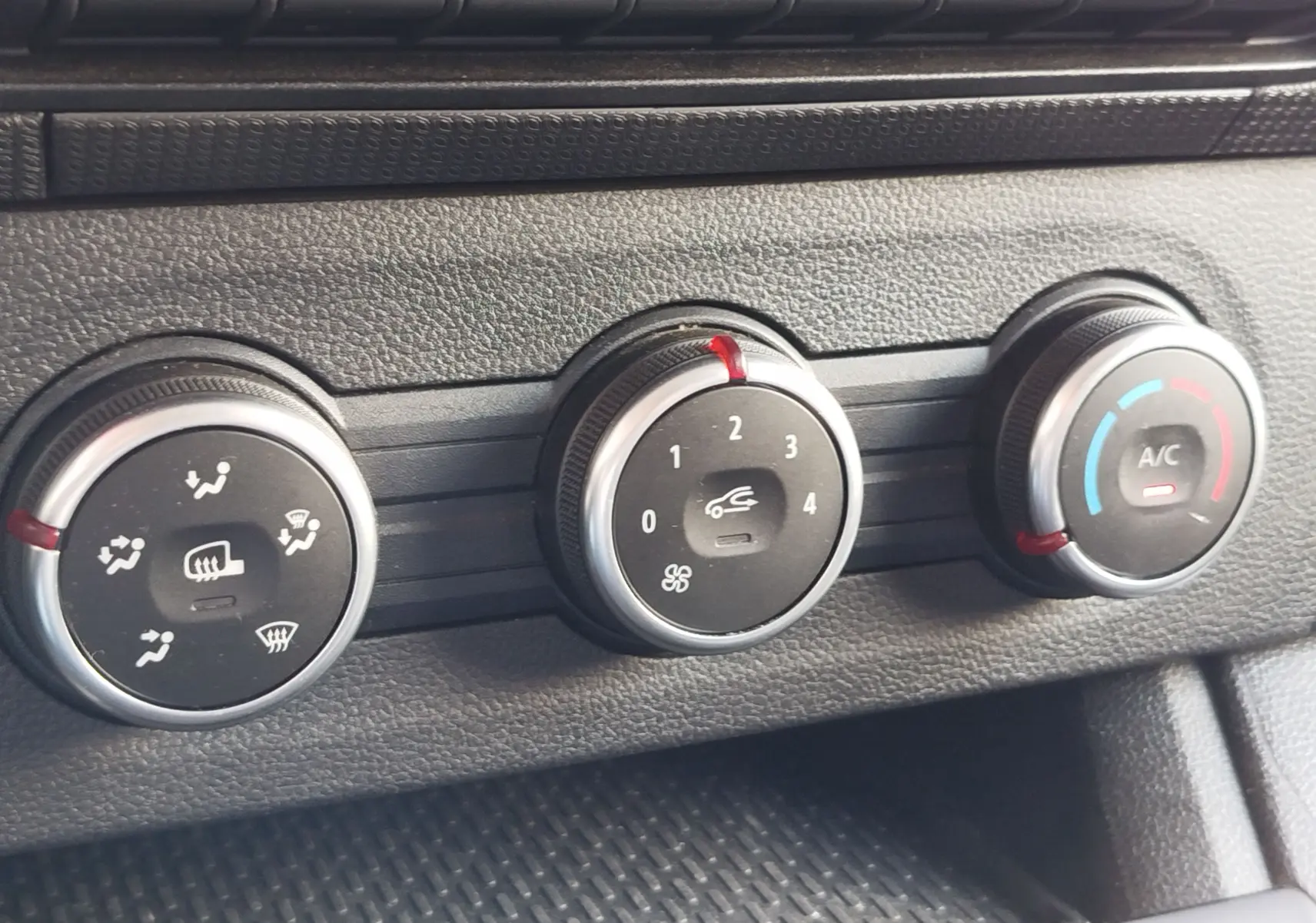 Gros plan sur les commandes de climatisation noires et argentées du Renault Kangoo 2023, avec réglages de ventilation et air conditionné.