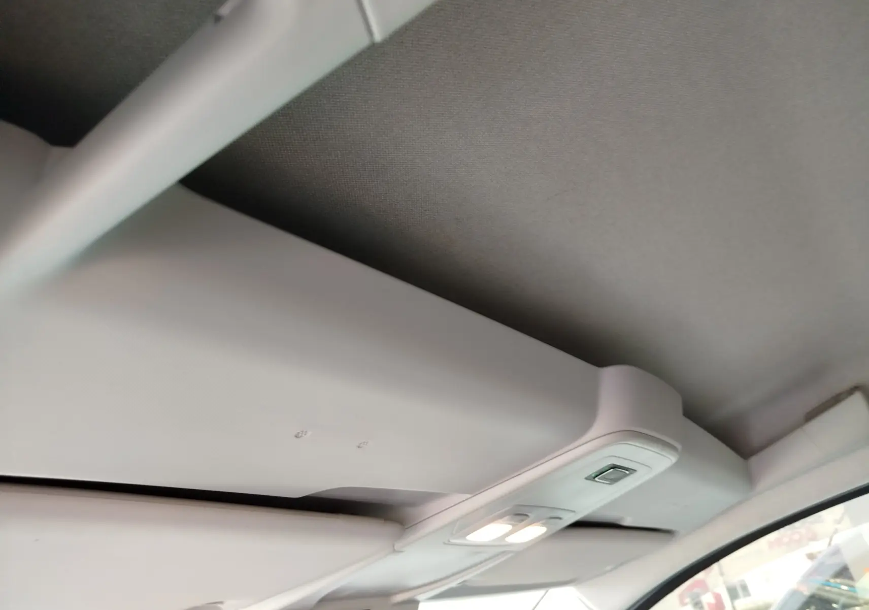 Vue intérieure du plafond avant du Renault Kangoo blanc, avec éclairage de cabine allumé et pare-soleil visible côté droit.