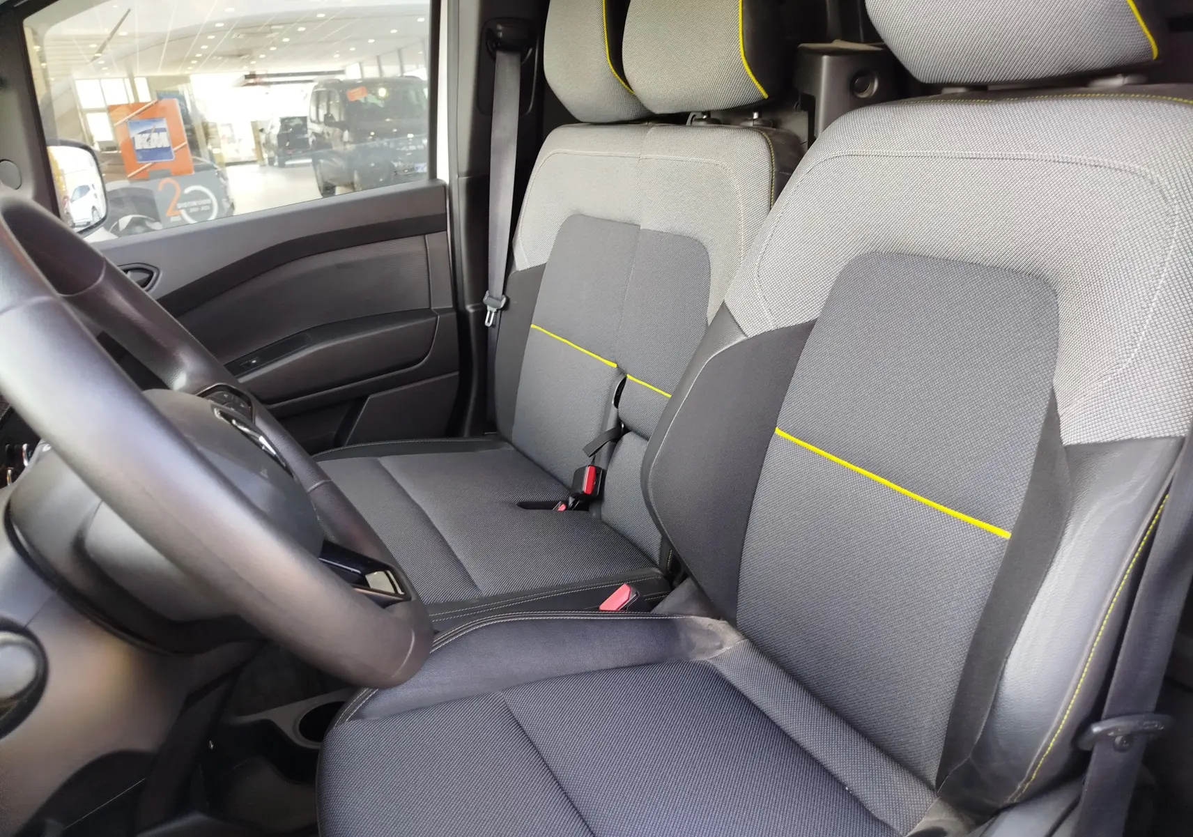 Vue intérieure côté conducteur du Renault Kangoo 1.5 Blue dCi 115ch 2023, sièges gris avec surpiqûres jaunes.