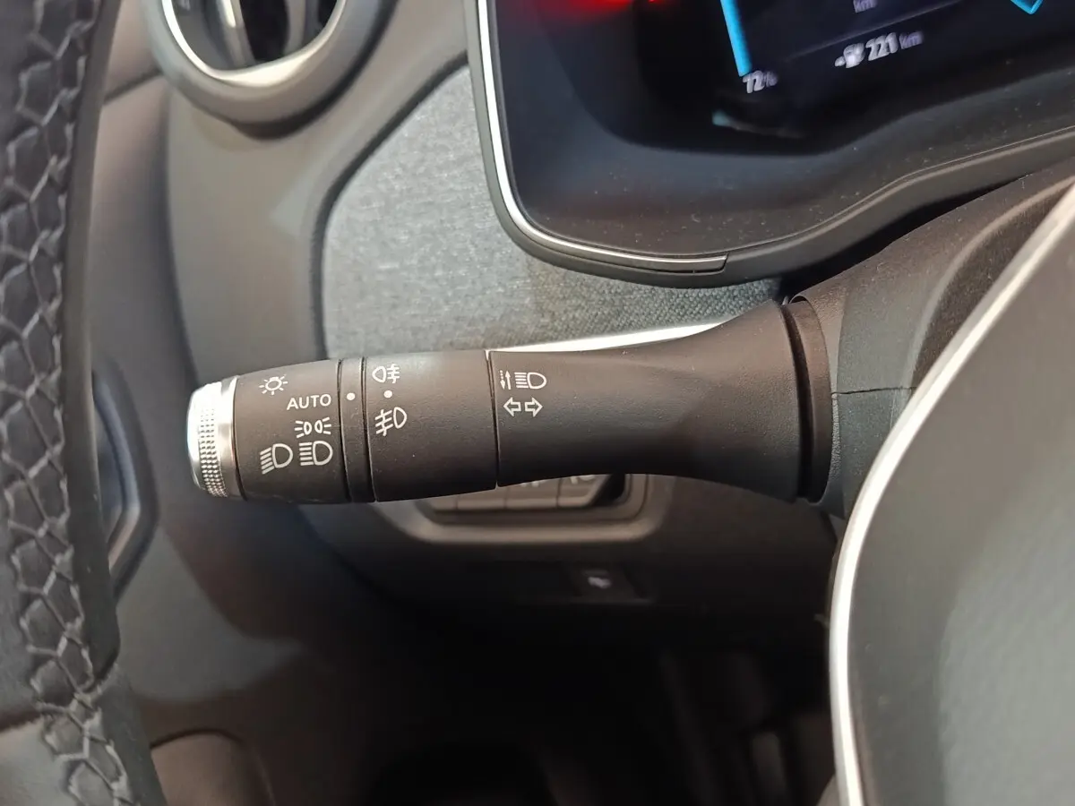 Gros plan sur la commande des feux et clignotants à gauche du volant dans l’habitacle d’une Renault ZOE blanche.