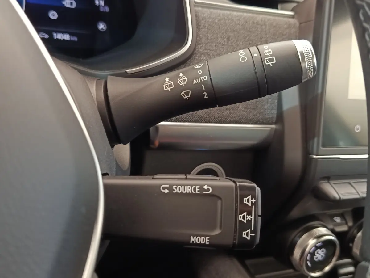 Gros plan sur les commandes au volant de la Renault ZOE Intens R110, intérieur noir avec écran tactile visible.
