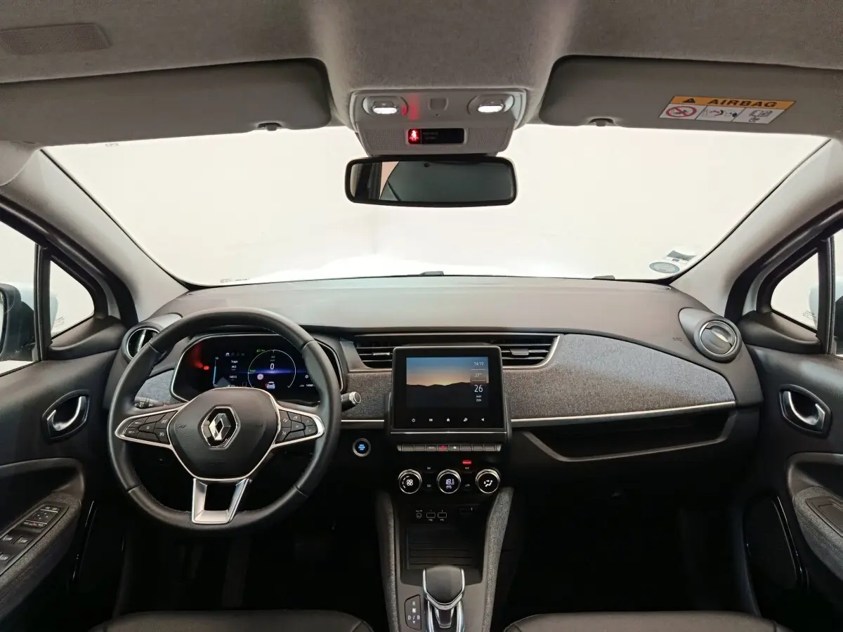 Vue frontale de l'intérieur de la Renault ZOE Intens R110 blanc, avec tableau de bord moderne et écran tactile central.