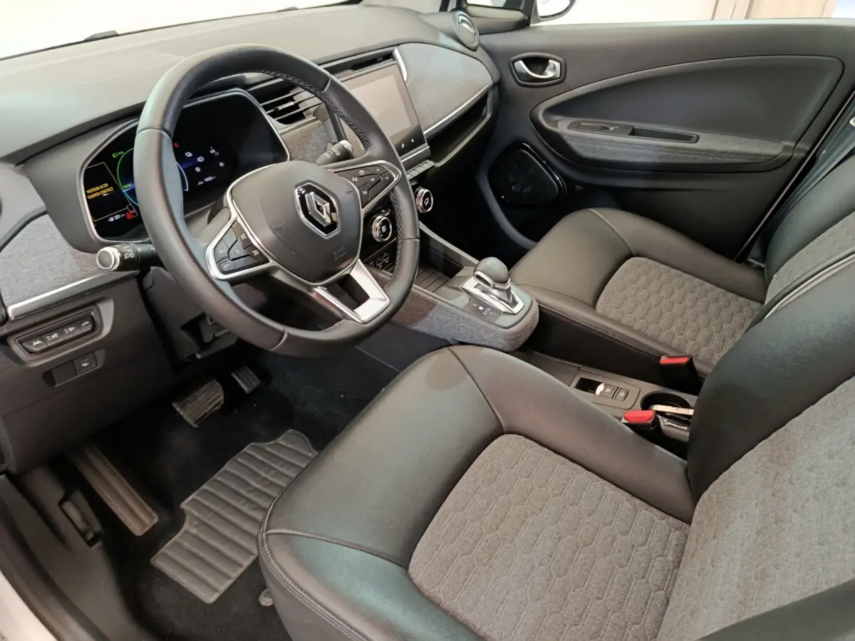 Vue intérieure côté conducteur de la Renault ZOE Intens R110 2021, montrant volant cuir, console centrale et sièges gris et noirs.