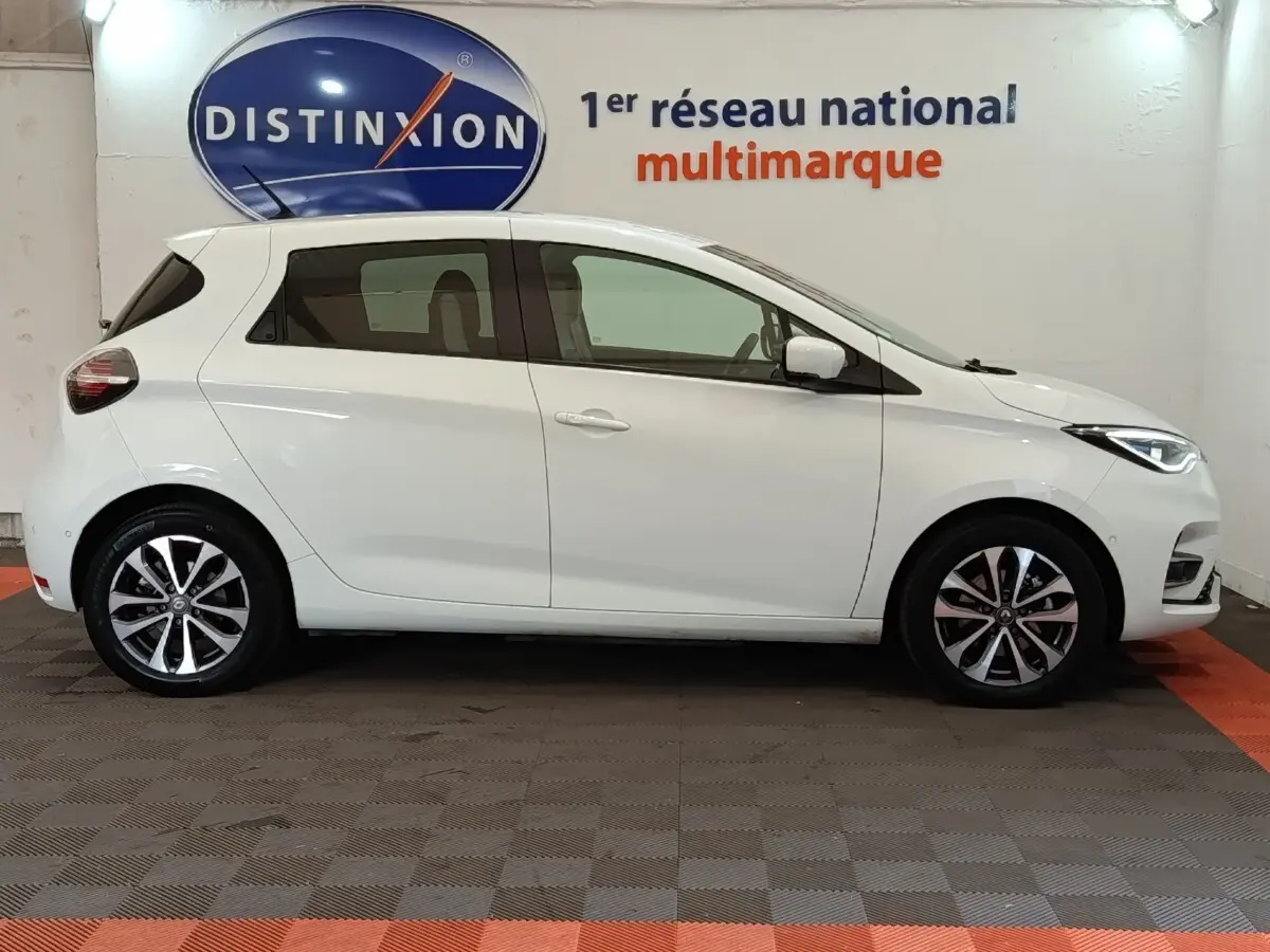Profil droit d'une Renault ZOE Intens R110 blanche de 2021, avec jantes alliage et feux avant LED visibles.