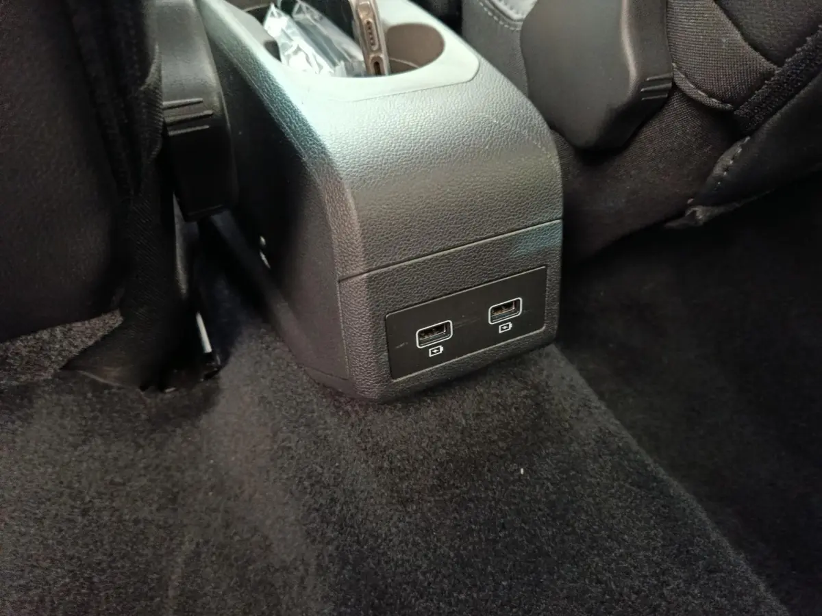 Vue rapprochée des ports USB arrière intégrés à la console centrale noire dans l’habitacle d’une Renault ZOE blanche.