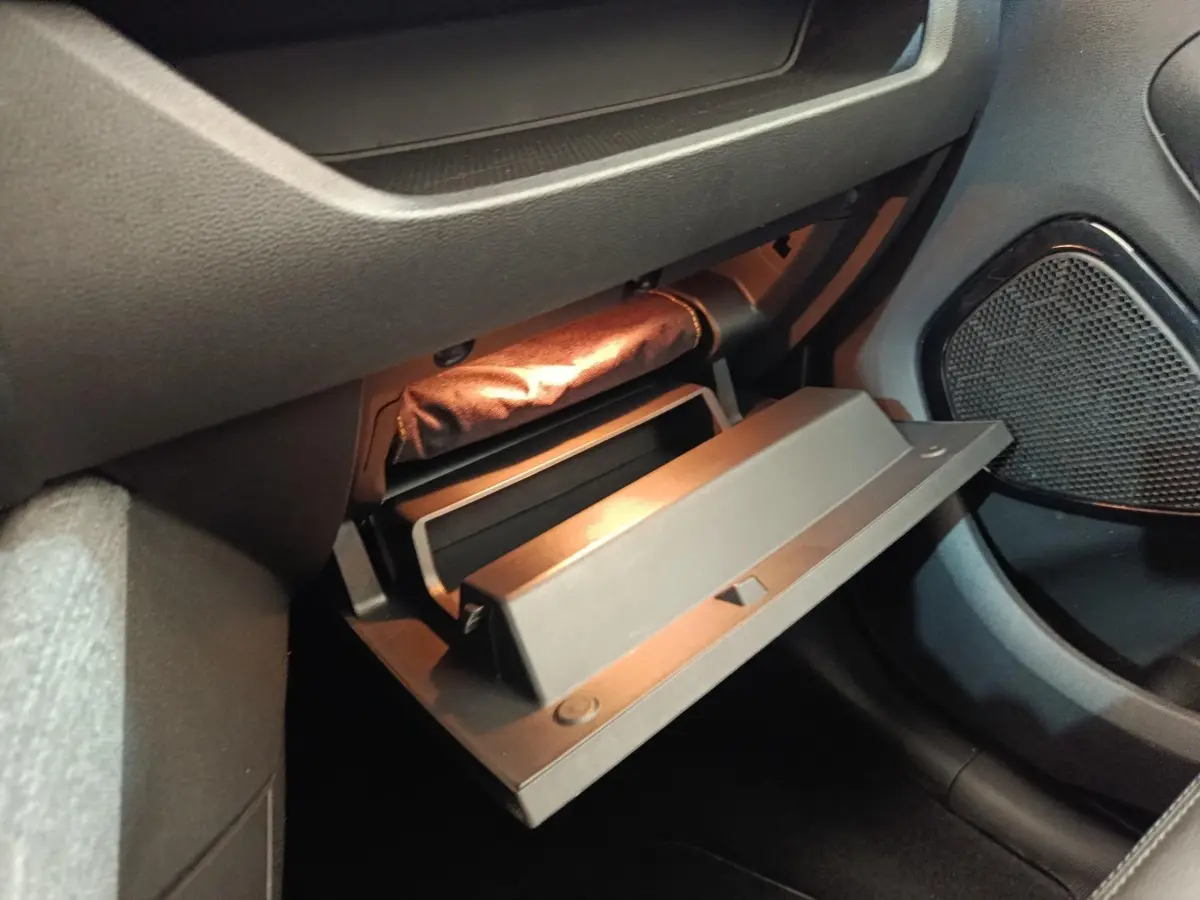 Vue rapprochée de la boîte à gants ouverte côté passager dans l’habitacle sombre d’une Renault ZOE blanche.