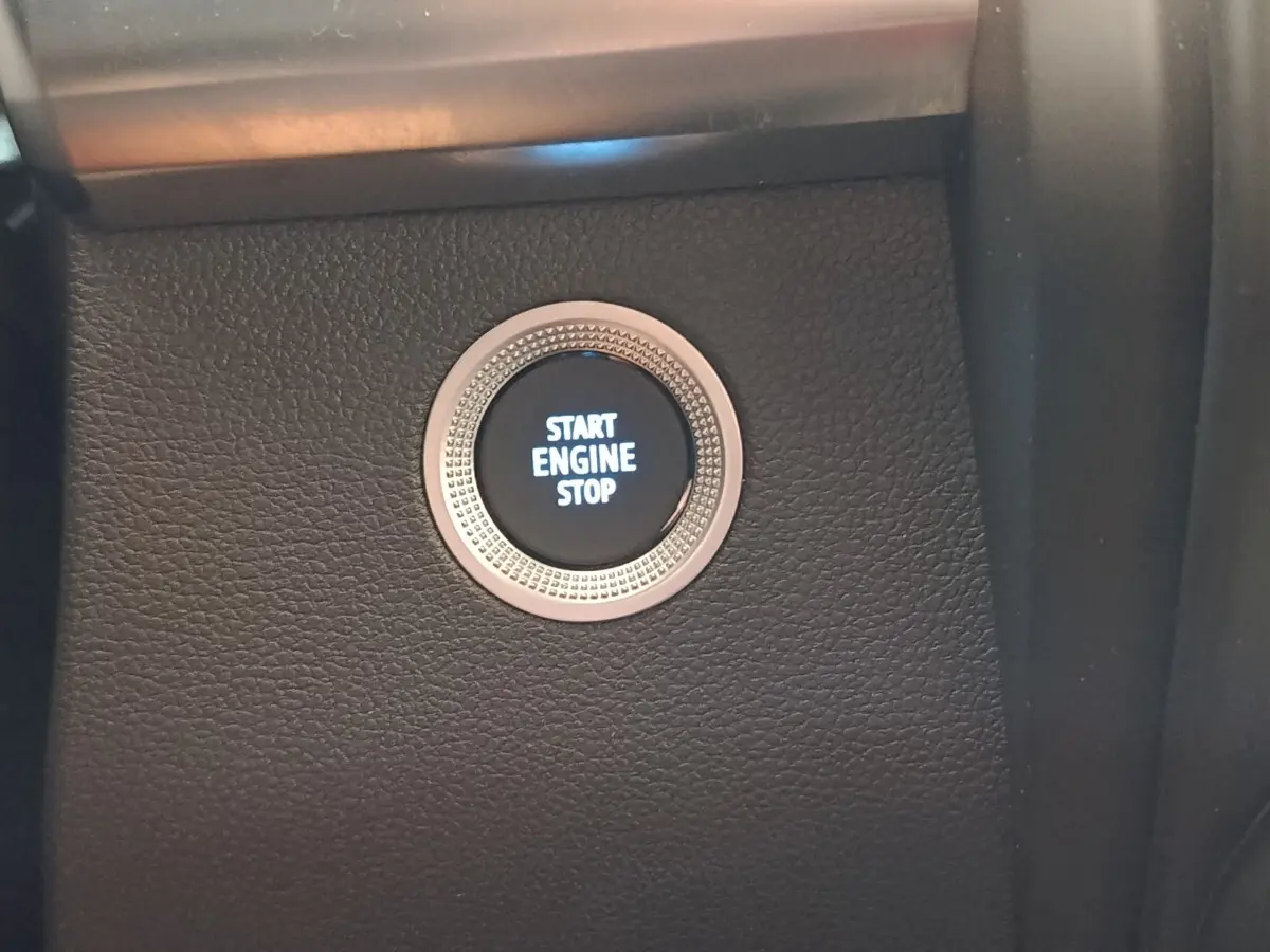 Gros plan sur le bouton démarrage "Start Engine Stop" entouré d'une bague argentée dans l'habitacle noir du Renault ZOE blanc.