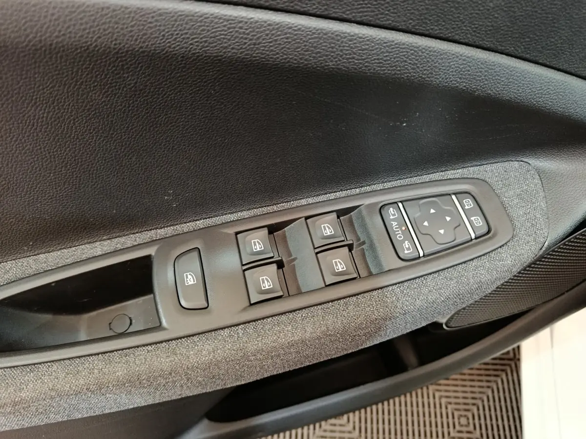 Détail des commandes des vitres et rétroviseurs sur la porte côté conducteur d’une Renault ZOE blanche Intens R110 2021.