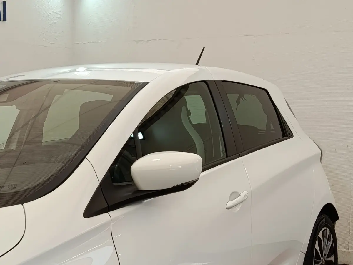 Vue de profil côté gauche sur une Renault ZOE Intens R110 blanche, avec rétroviseur et poignées assortis.