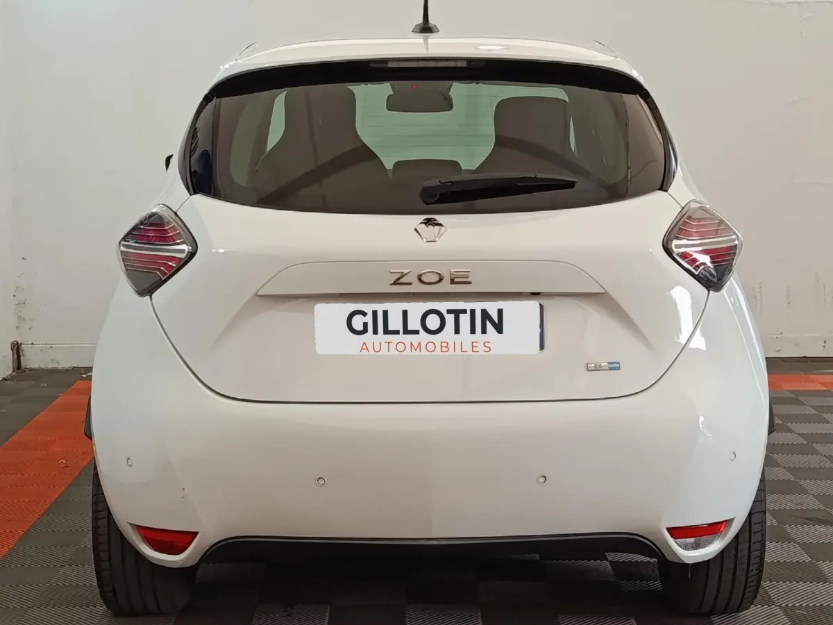 Vue arrière d'une Renault ZOE blanche 2021 avec feux arrière distinctifs et logo ZOE centré sur le hayon.