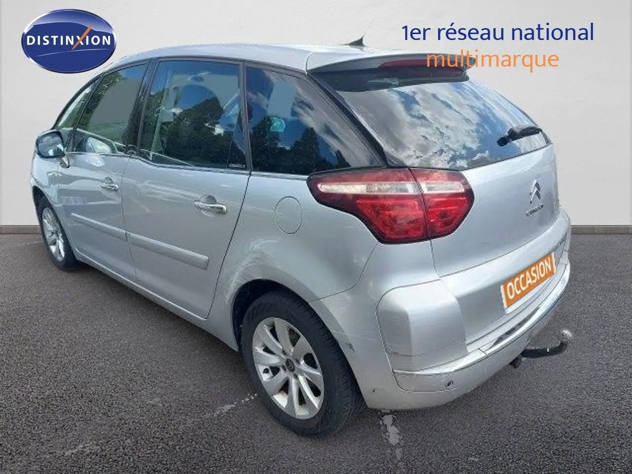 Vue 3/4 arrière droite d'une Citroën C4 Picasso gris alu métal avec attelage et feux arrière LED.