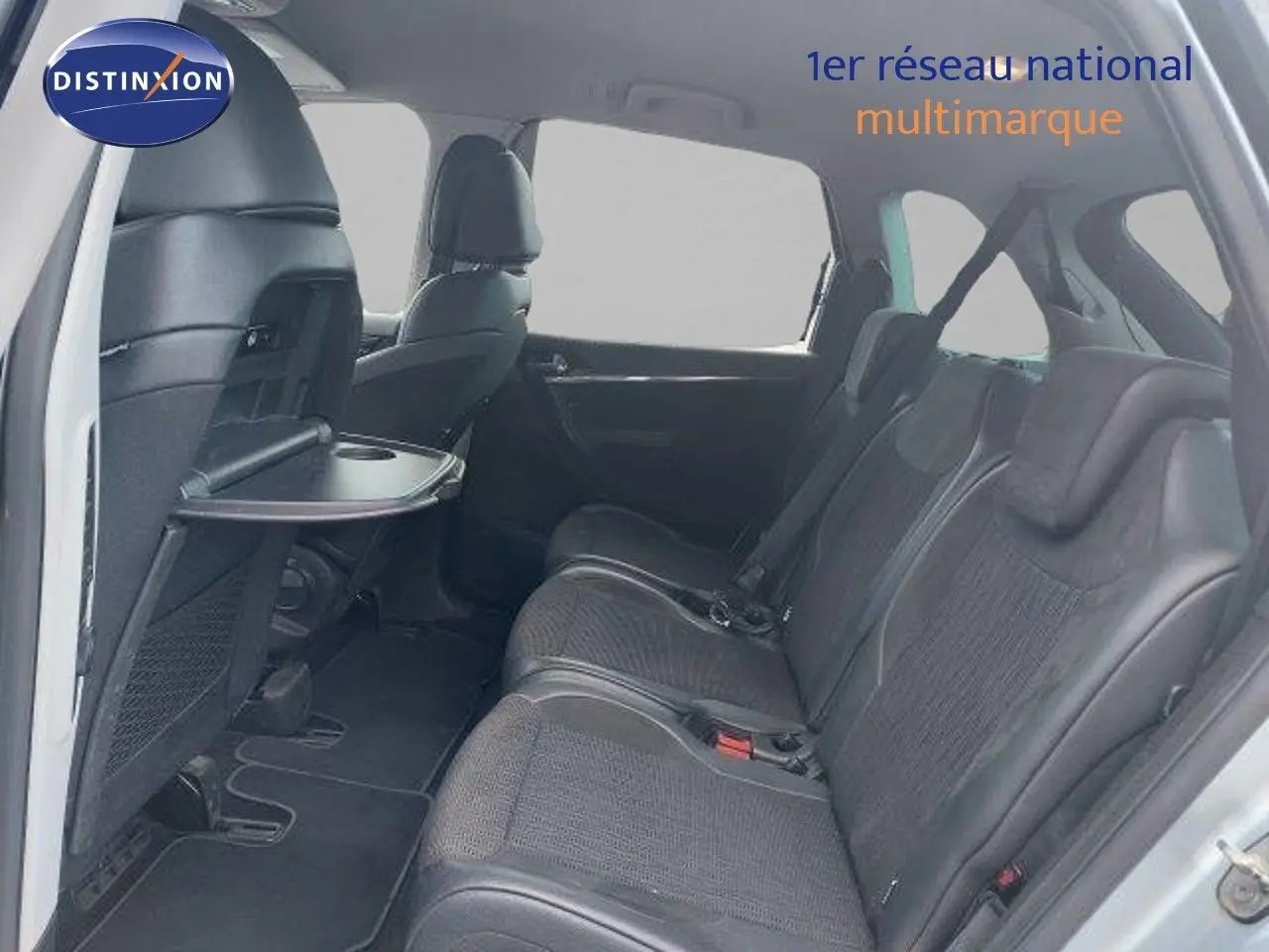 Vue intérieure côté droit arrière de la Citroën C4 Picasso gris alu, sièges en cuir noir avec tablette rabattable.