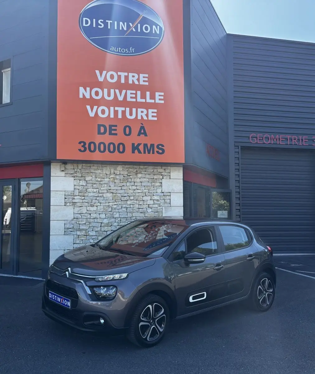 Citroën C3 gris foncé vue 3/4 avant droit, avec signature lumineuse distinctive et jantes stylisées.