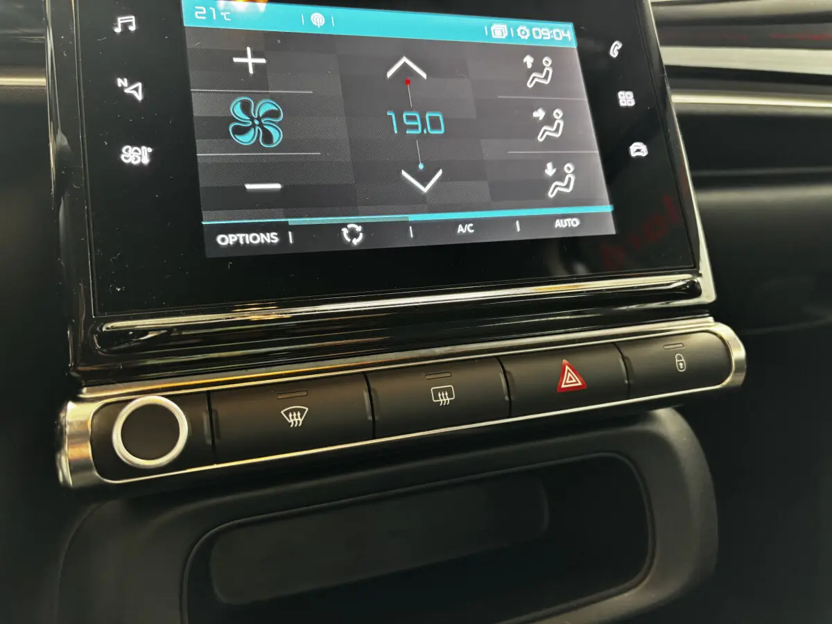Gros plan sur l'écran tactile central et les commandes de climatisation d'une Citroën C3 gris foncé 2024.