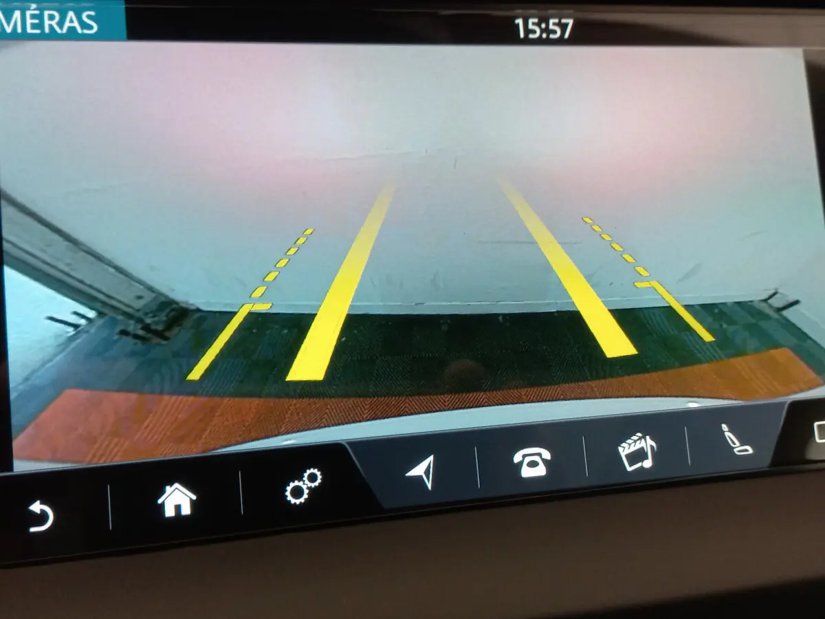 Vue de la caméra de recul du Jaguar E-PACE blanc, affichant les lignes de guidage jaunes sur un sol carrelé.