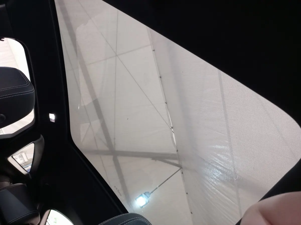 Toit panoramique en verre de l'intérieur d'un Jaguar E-PACE blanc, vue vers le ciel depuis l'arrière