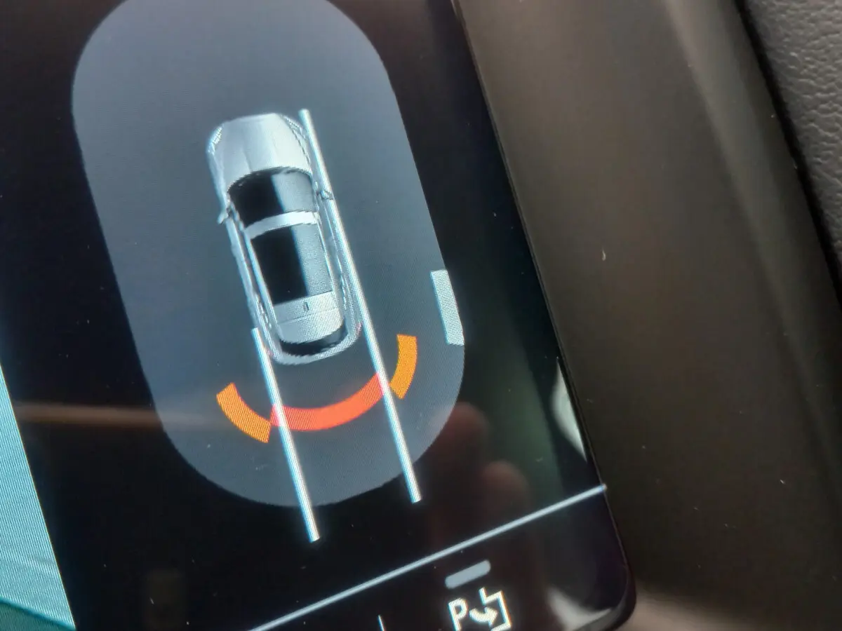 Affichage tactile montrant le Jaguar E-PACE blanc en vue aérienne avec assistance au stationnement arrière active.
