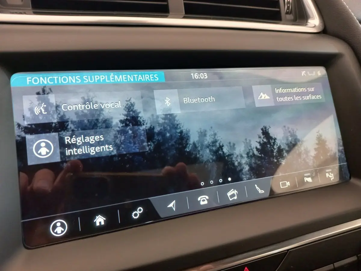 Écran tactile du tableau de bord du Jaguar E-PACE blanc 2019 affichant les fonctions vocales et Bluetooth.