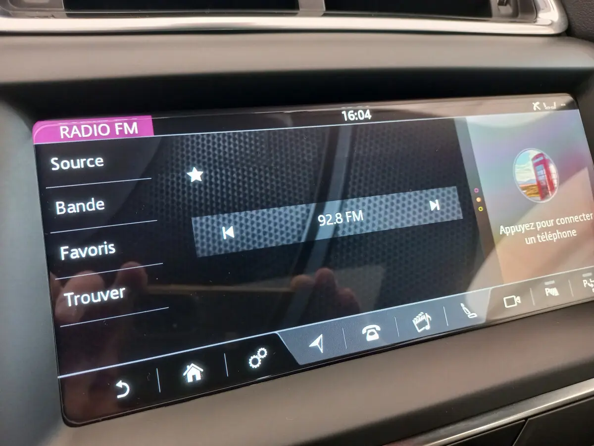 Écran tactile central de la Jaguar E-PACE blanc 2019 affichant la radio FM sur 92.8 MHz en intérieur.