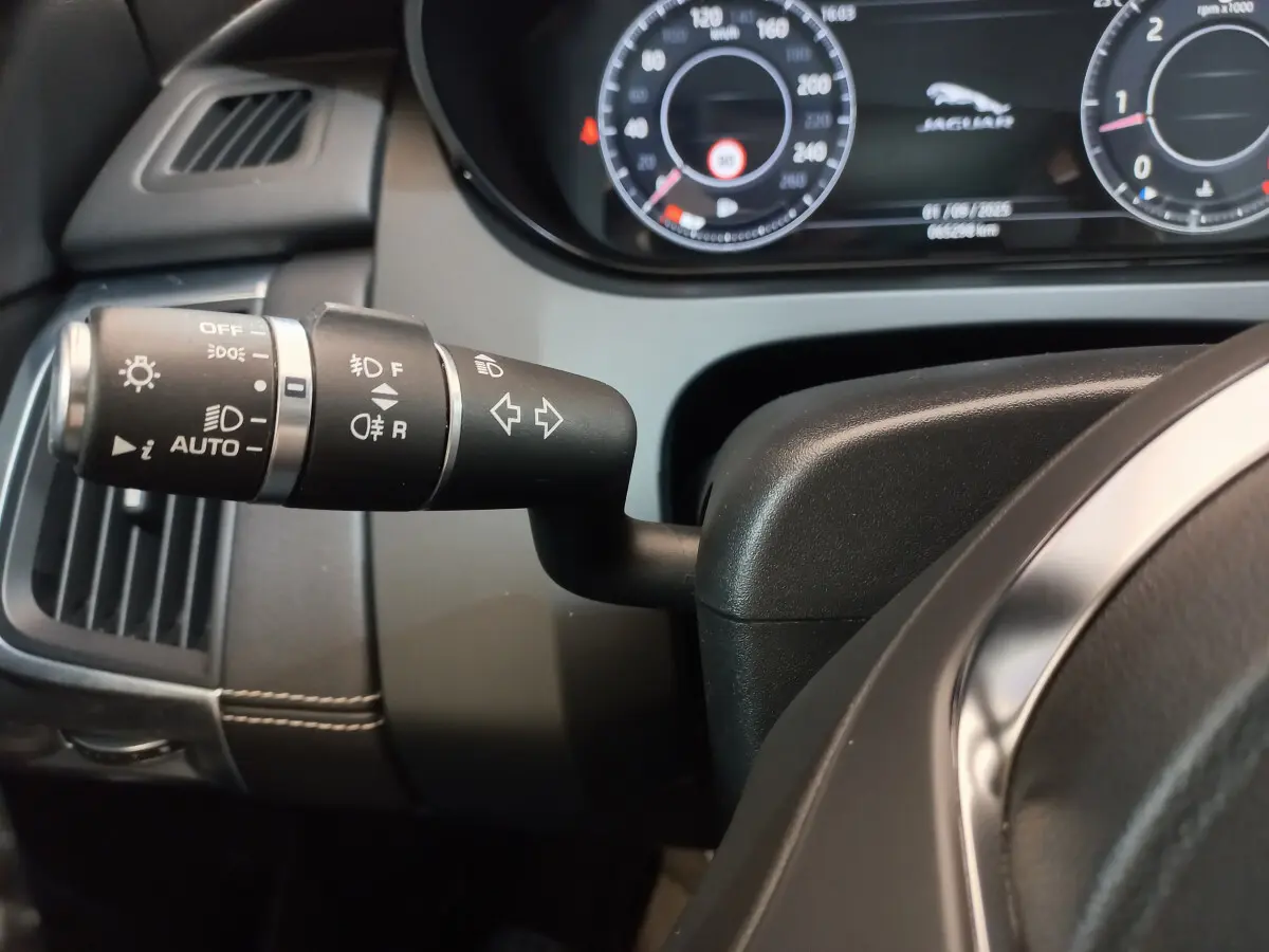 Gros plan sur la manette de clignotants noire à gauche du volant cuir du tableau de bord du Jaguar E-PACE blanc 2019.