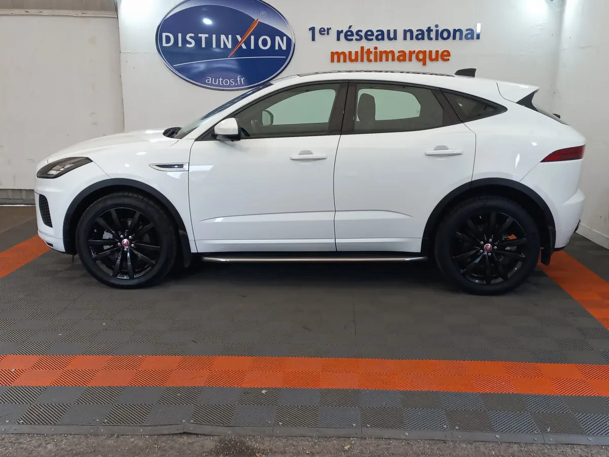Profil côté gauche d'un Jaguar E-PACE blanc 2019 avec jantes noires et lignes sportives marquées.
