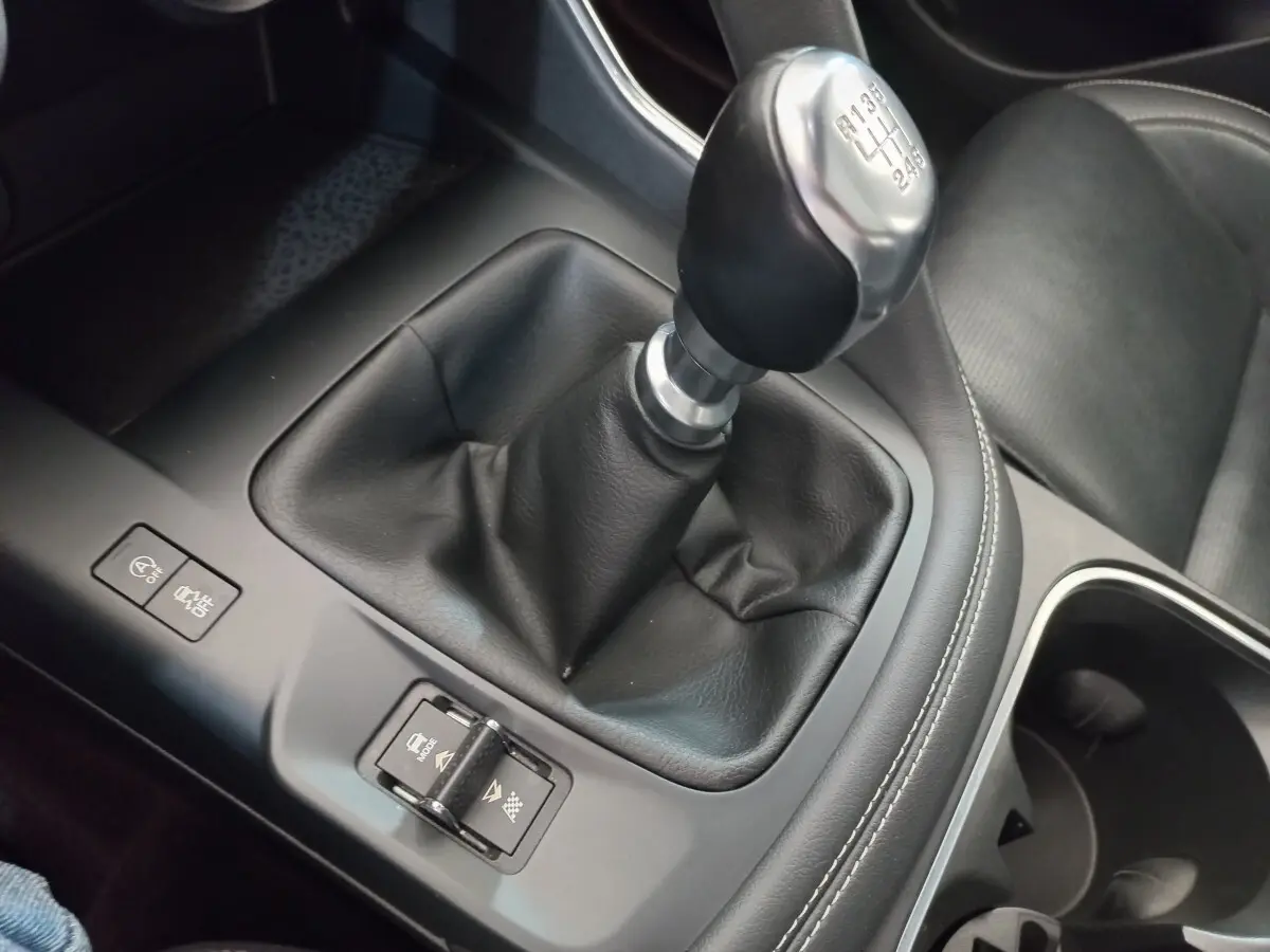 Gros plan sur levier de vitesse manuel noir et console centrale grise dans l'habitacle du Jaguar E-PACE blanc.