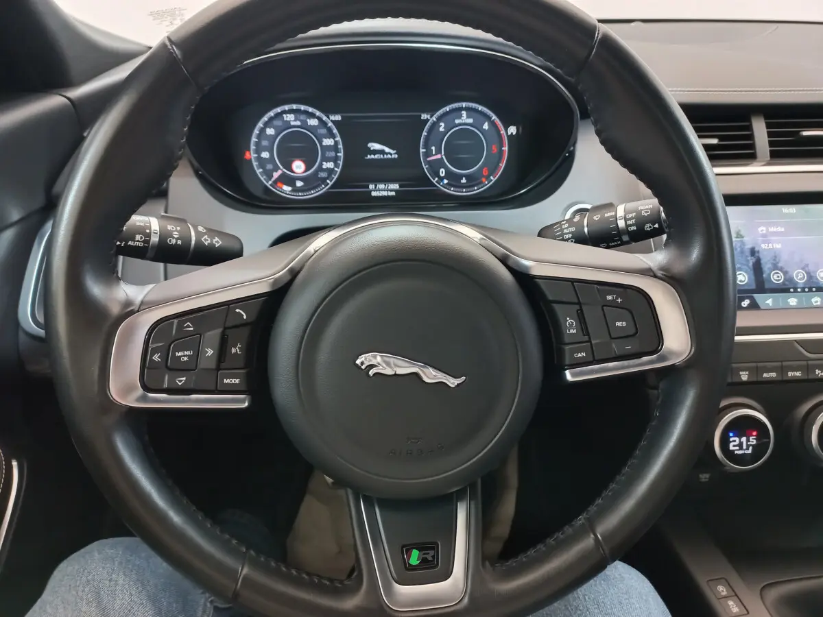 Vue rapprochée du volant cuir noir d'une Jaguar E-PACE 2019 avec tableau de bord digital et écran tactile central.
