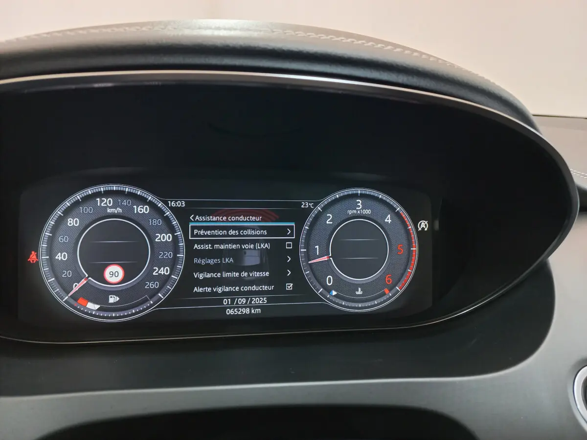 Tableau de bord numérique de Jaguar E-PACE blanc, affichant les aides à la conduite et compteurs ronds lumineux.