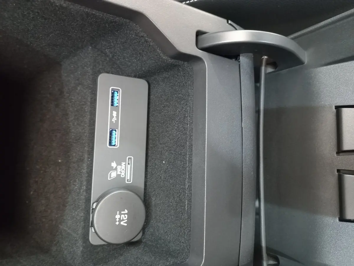 Gros plan sur la prise 12V et ports USB dans le rangement central du Jaguar E-PACE blanc de 2019.