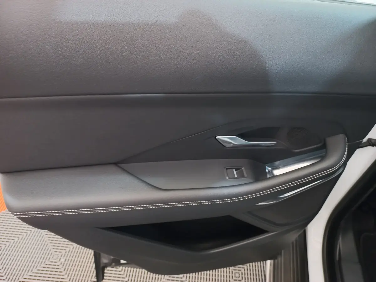 Gros plan sur la porte intérieure côté droit d'une Jaguar E-PACE blanche avec garniture noire et surpiqûres blanches.