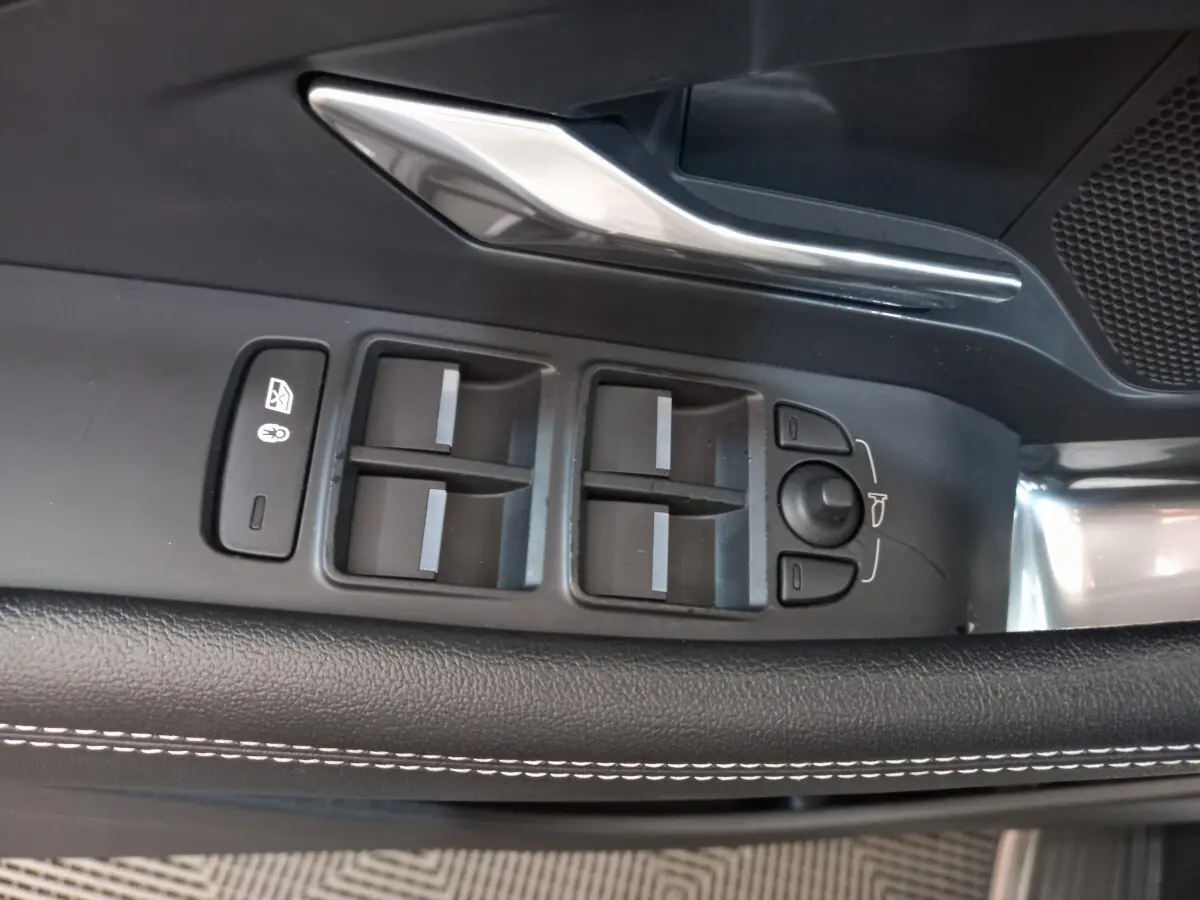 Gros plan sur les commandes de lève-vitres et rétroviseurs côté conducteur du Jaguar E-PACE blanc, avec surpiqûres blanches.