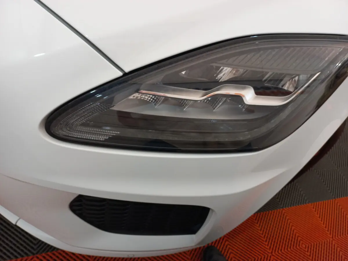 Gros plan sur le phare avant droit du Jaguar E-PACE blanc, soulignant son design LED distinctif.