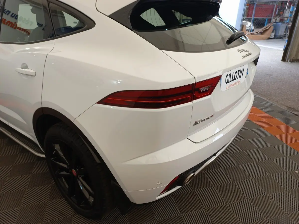 Vue 3/4 arrière droite d'un Jaguar E-PACE blanc avec feux arrière allongés et jantes noires brillantes.