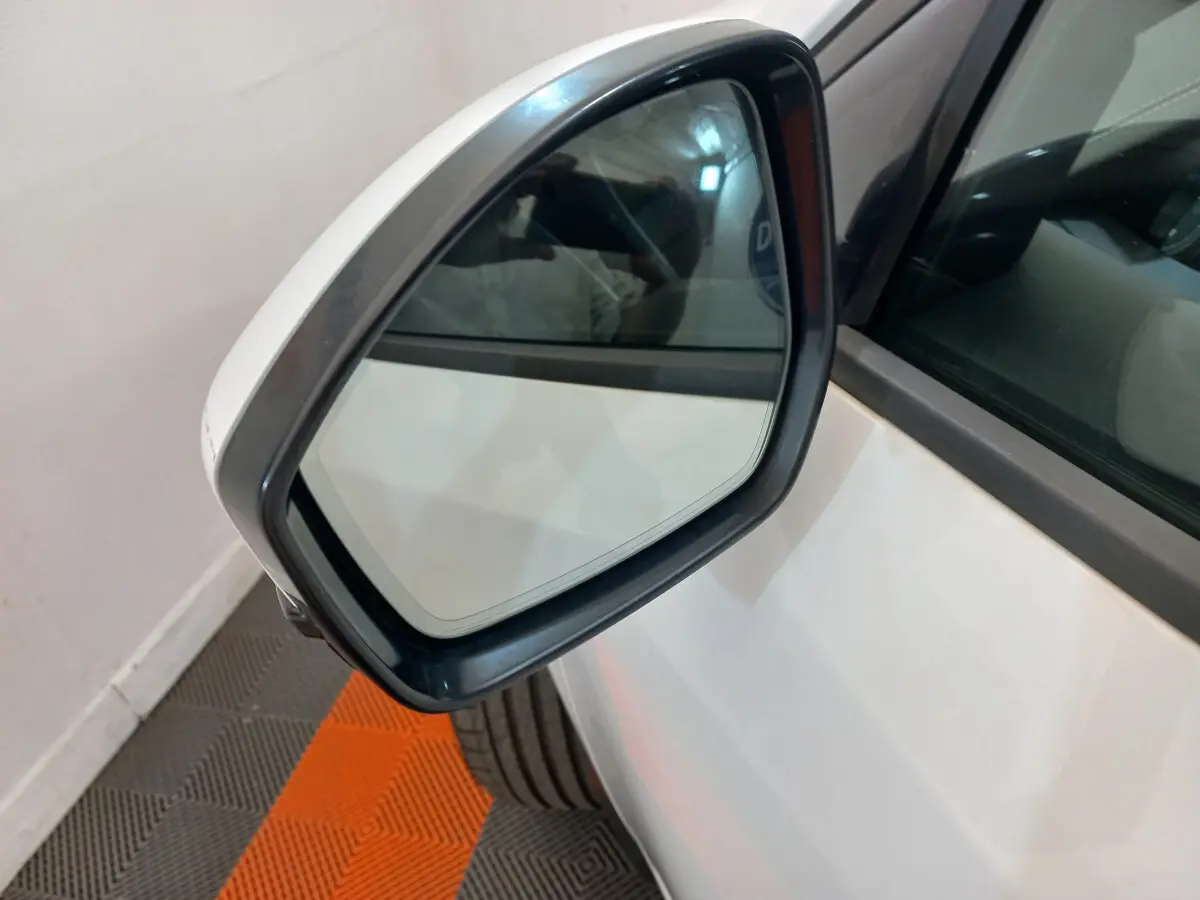Rétroviseur extérieur côté gauche blanc d'un Jaguar E-PACE 2019 avec carrosserie blanche visible en arrière-plan.