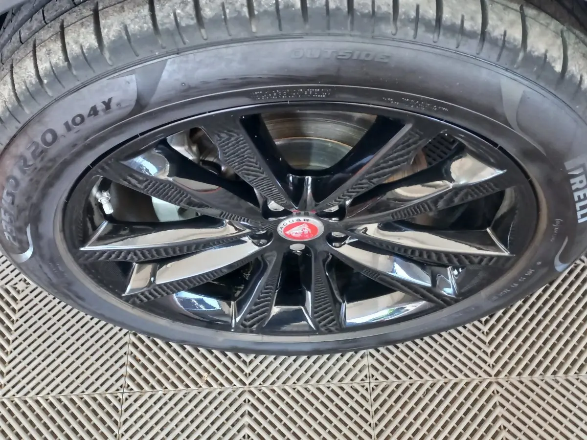 Gros plan sur la jante noire brillante avec logo Jaguar rouge au centre du SUV blanc Jaguar E-PACE 2019.