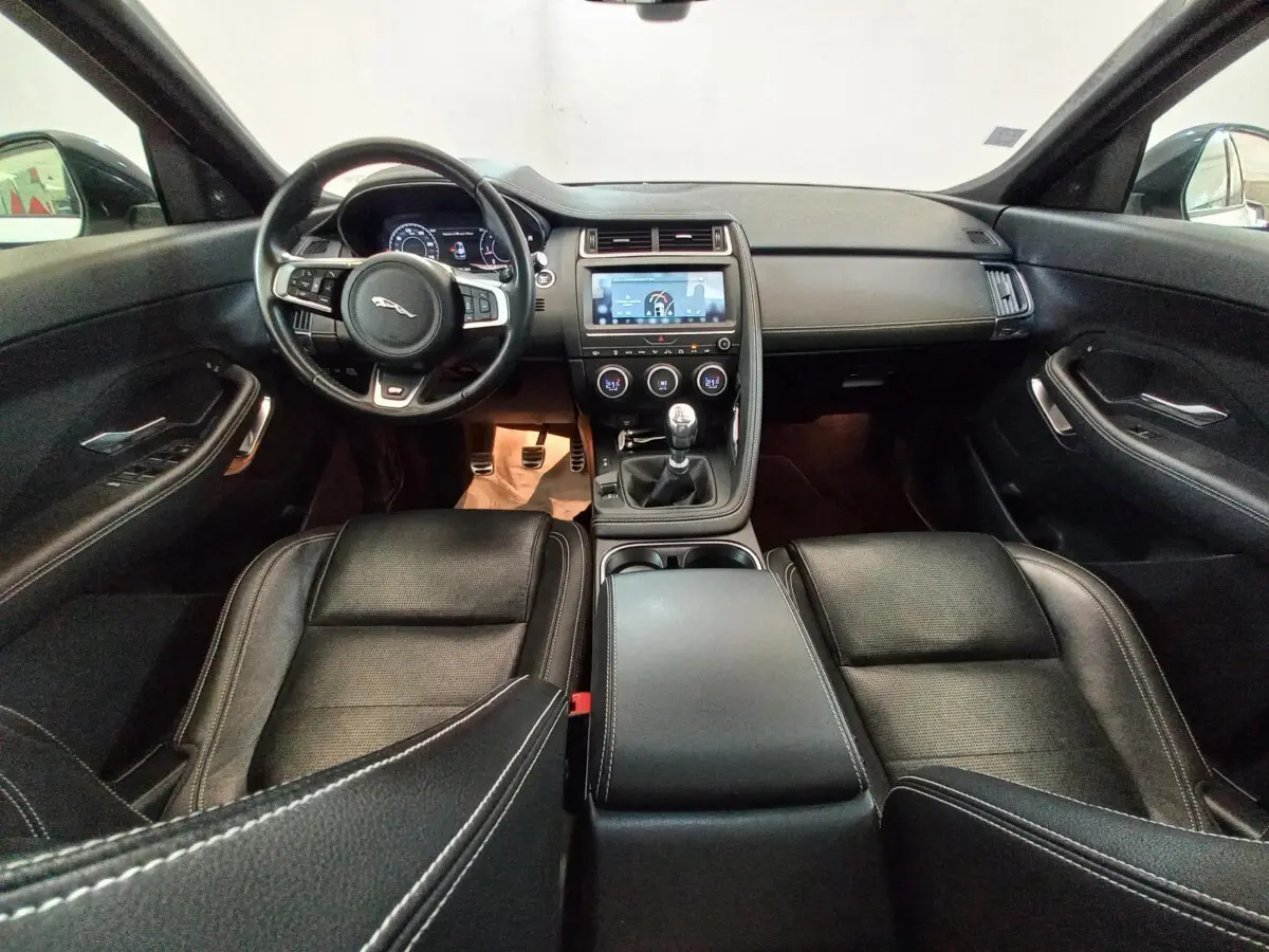 Intérieur noir du Jaguar E-PACE 2019 vu de face, avec volant cuir, tableau de bord digital et boîte manuelle.