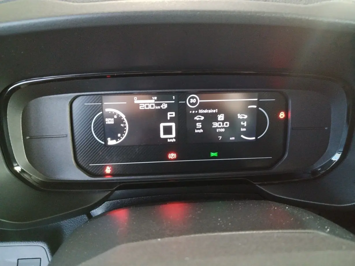 Tableau de bord numérique du Citroën Berlingo 2025 affichant vitesse, consommation et alertes en vue frontale rapprochée.