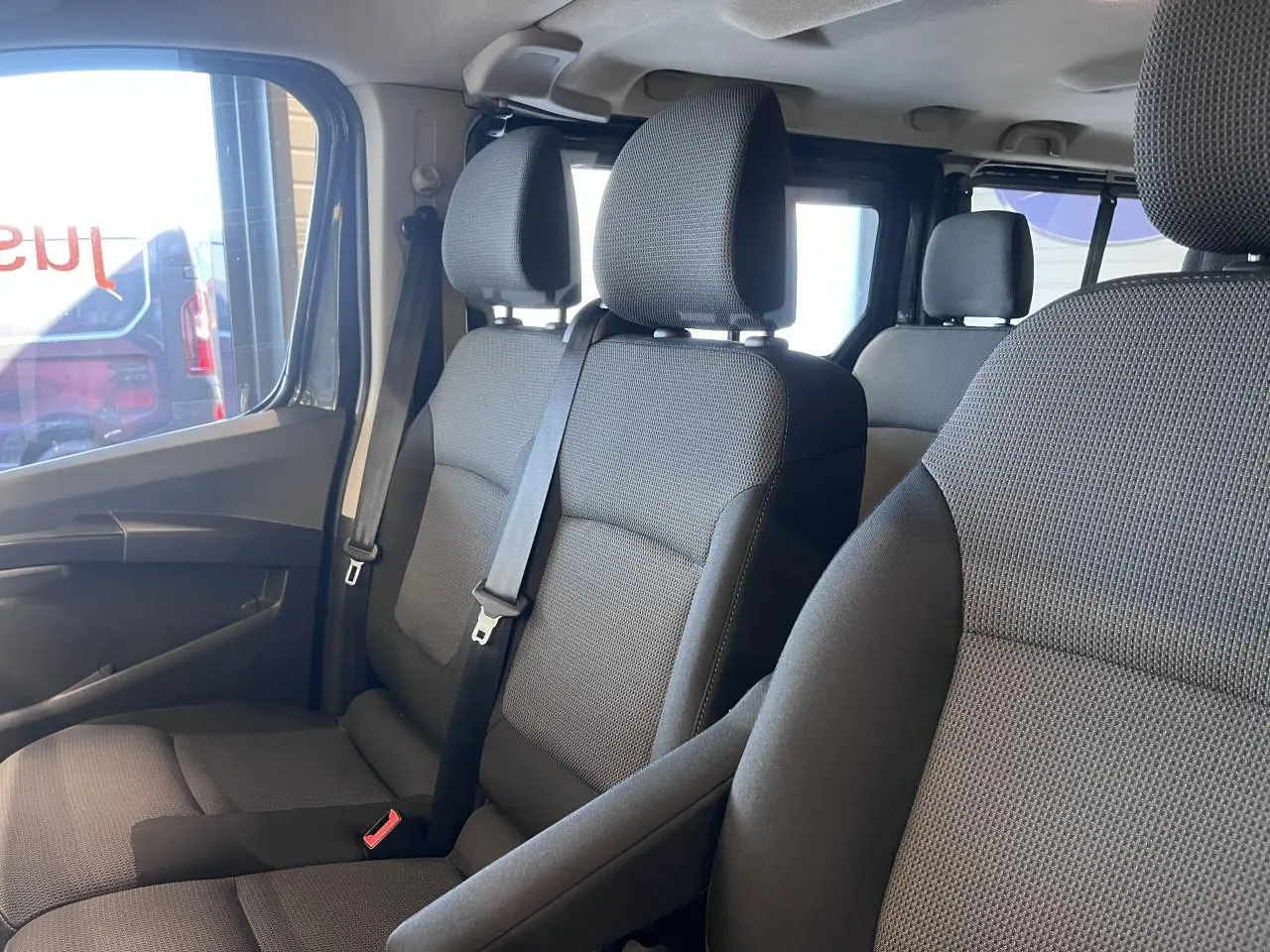Vue intérieure côté gauche sur les sièges avant gris foncé du Renault Trafic Combi 9 places, tissu Kompo Black.