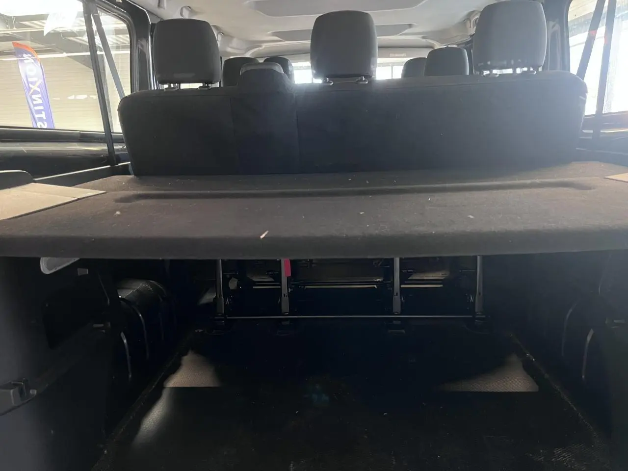 Vue arrière intérieure du Renault Trafic Combi gris foncé, montrant la banquette arrière et le cache-bagages déployé.